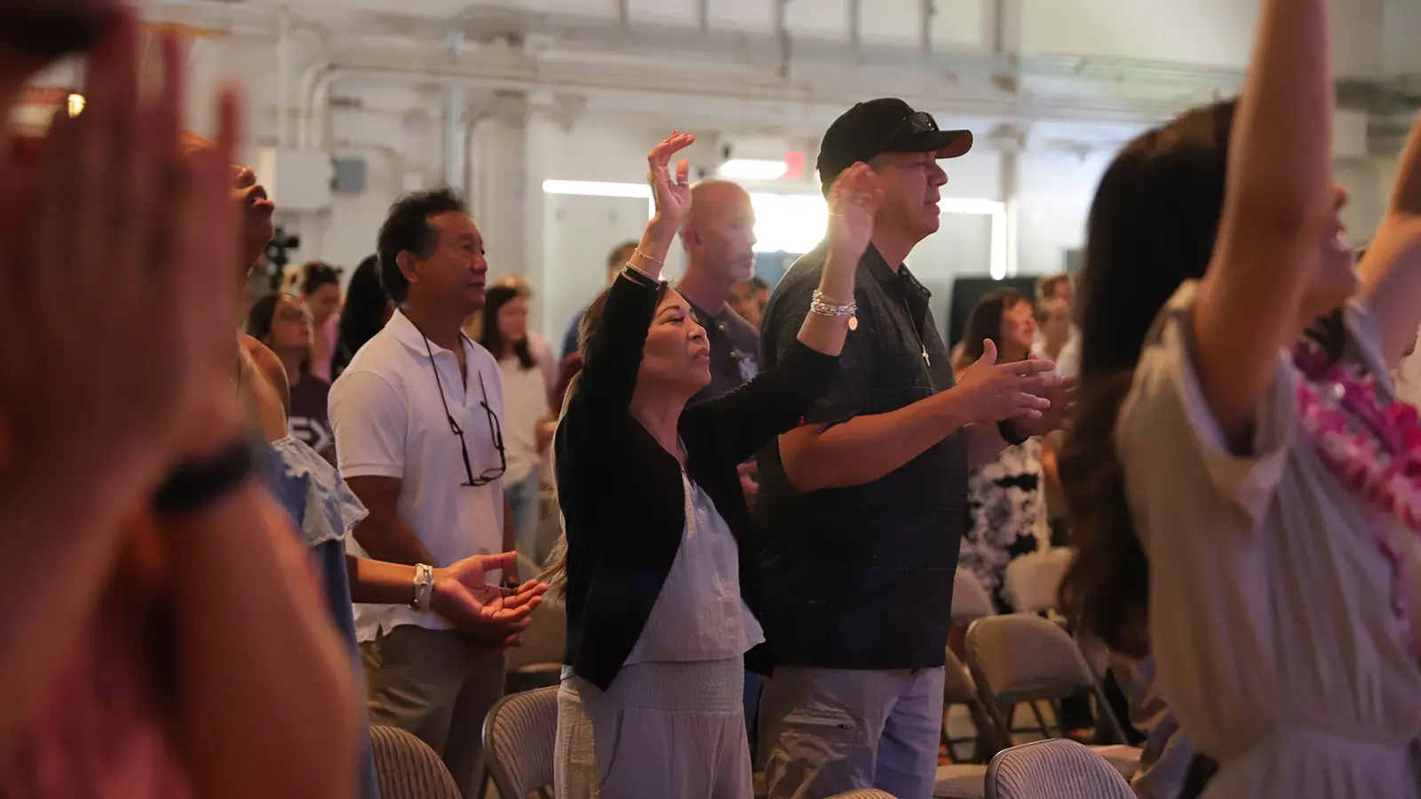 People worshiping with hands raised during a Sunday service