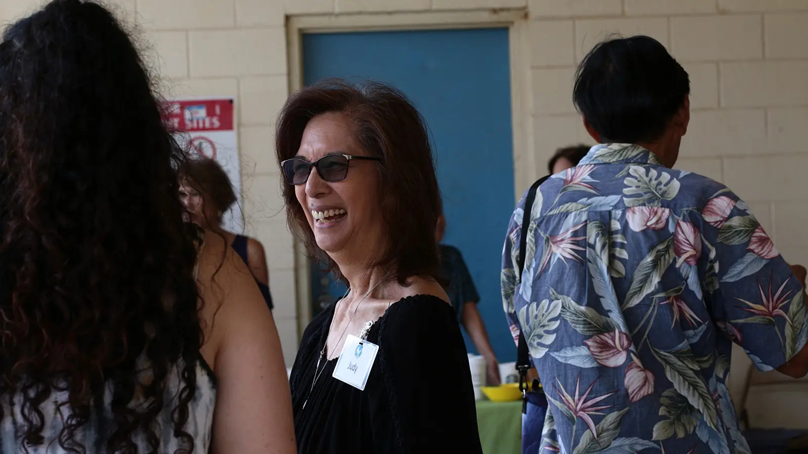 A smiling woman with a name badge greeting people after service