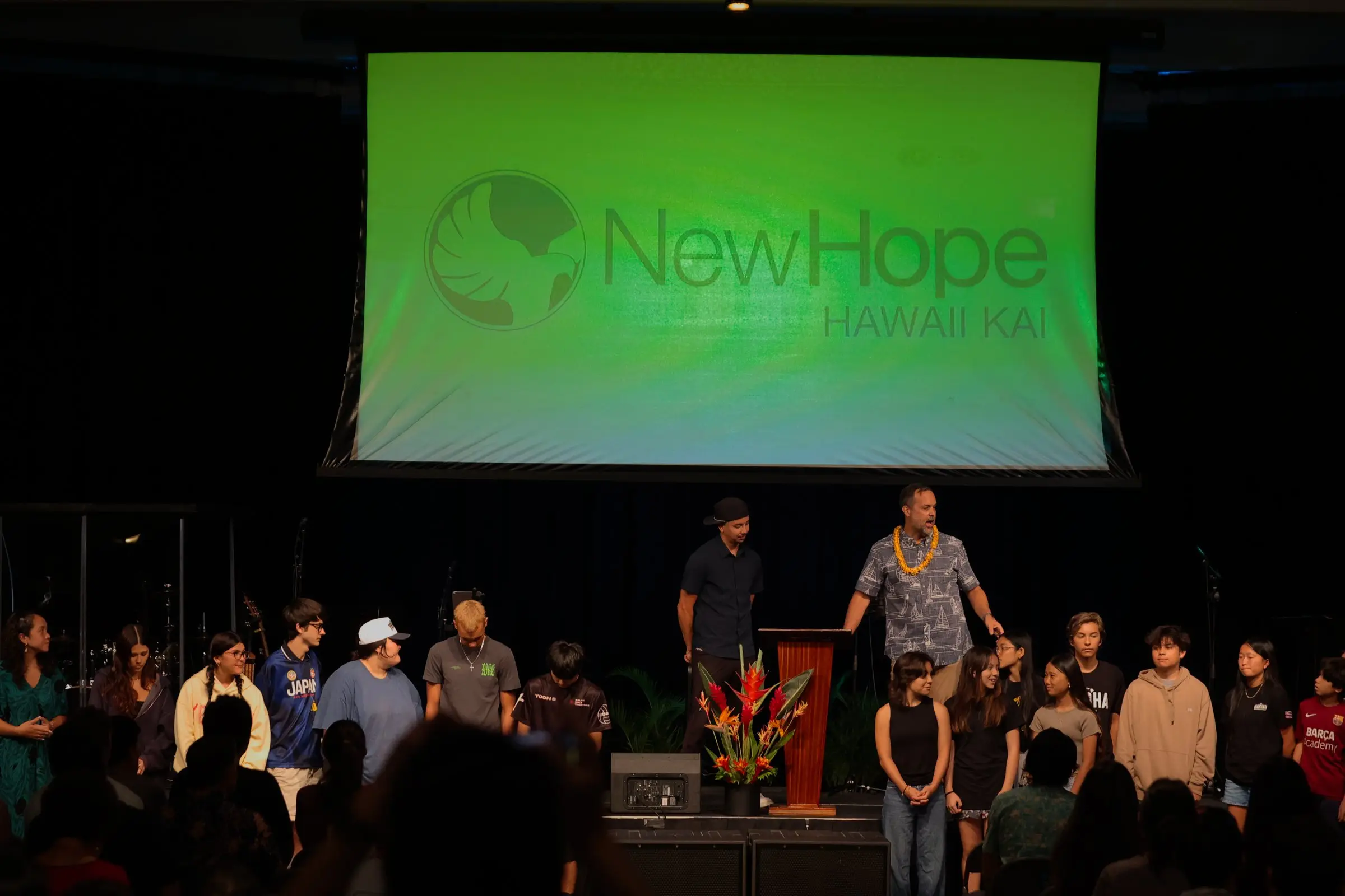 Sunday service in the Kaiser High School cafeteria, the New Hope Hawaii Kai logo on the big screen