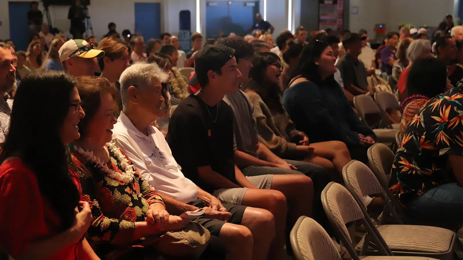 The congregation seated in folding chairs, smiling and laughing during a Sunday service