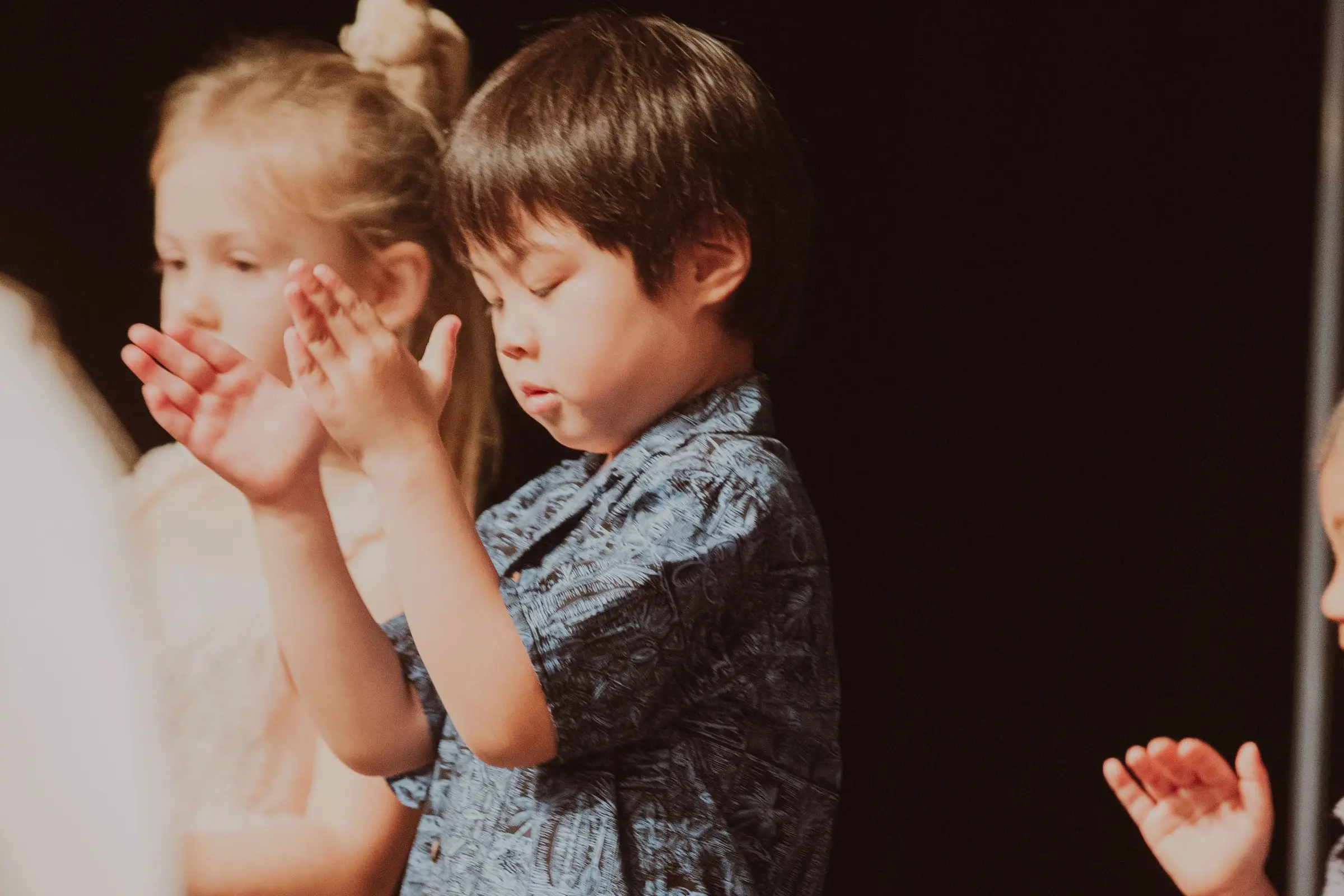 A boy with his eyes closed clapping along to a song on Easter Sunday
