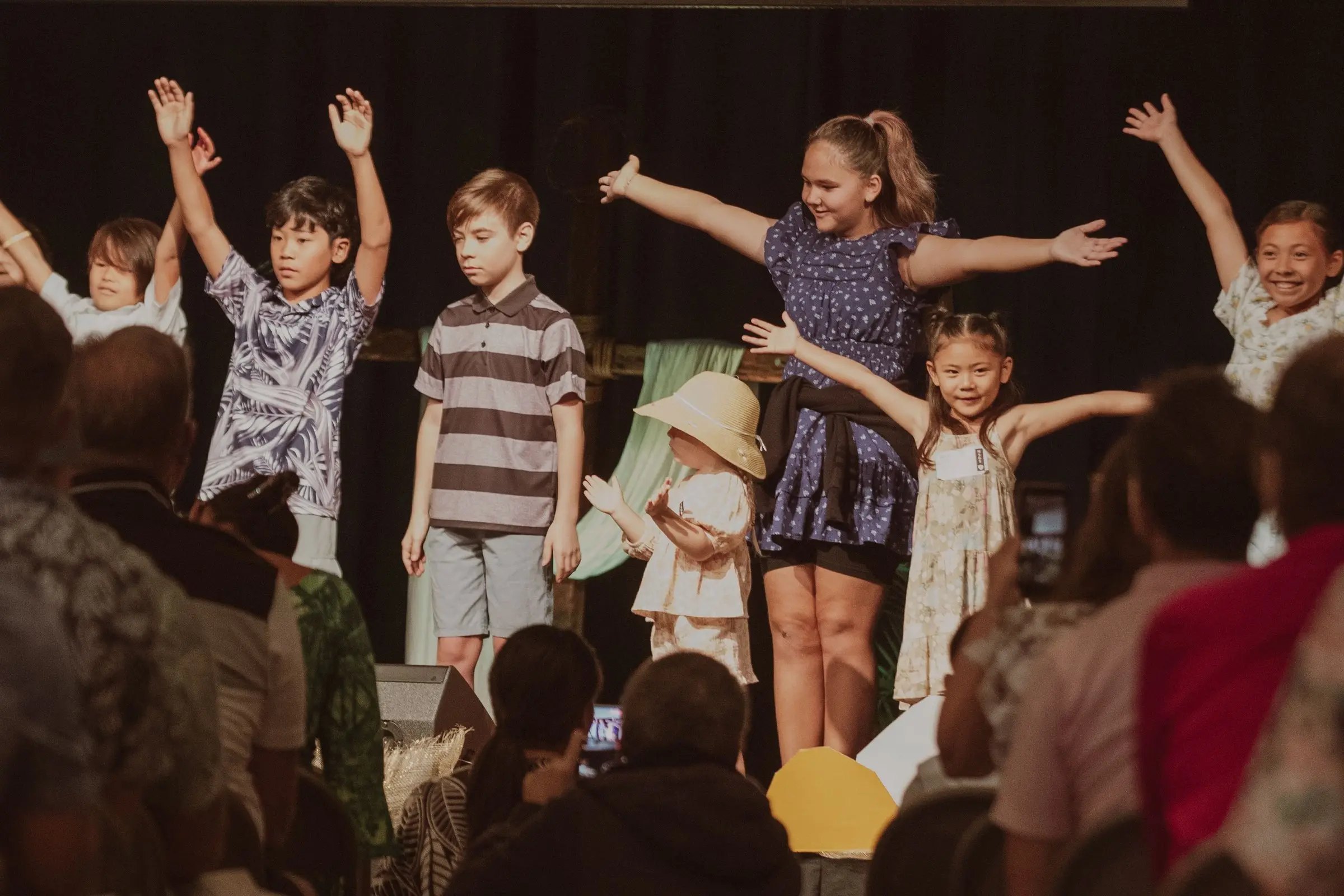 Kids with their arms open wide singing on stage on Easter Sunday while the church watches