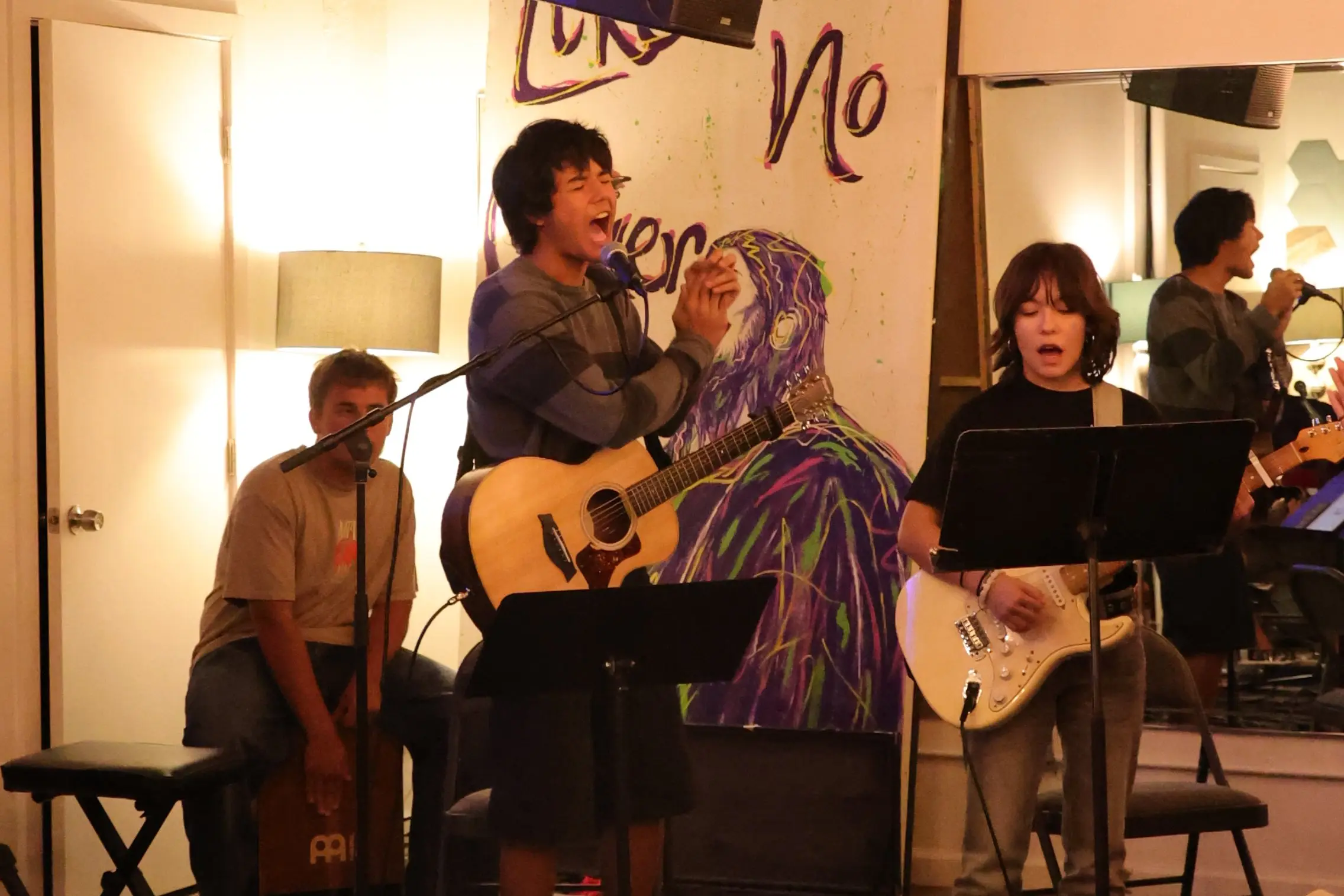 The student worship band playing guitars and singing under string lights at the Ministry Center