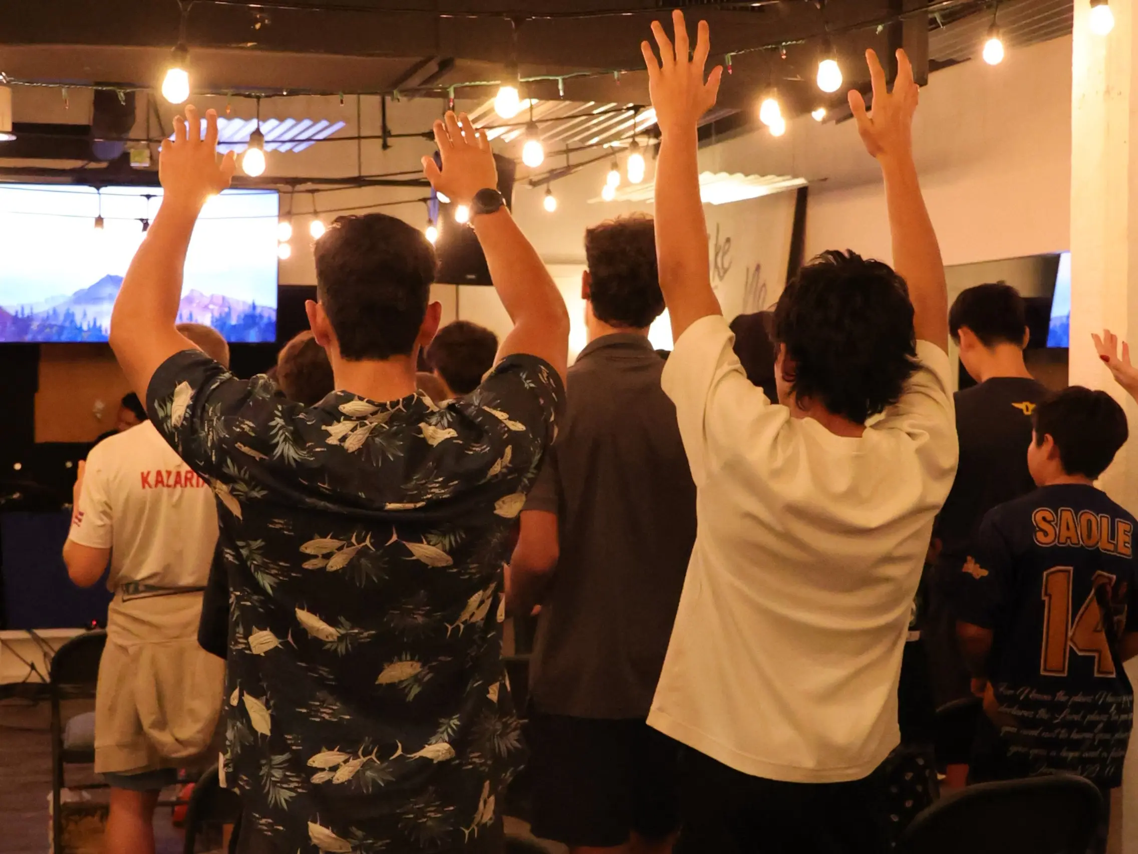 Students with their hands raised during worship on a youth night at the Ministry Center